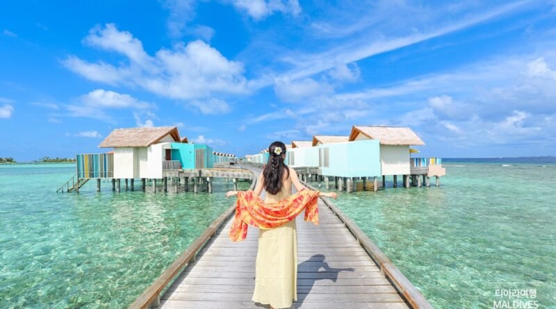 Woman in traditional dress walking on overwater bungalow boardwalk at Hard Rock Hotel Maldives