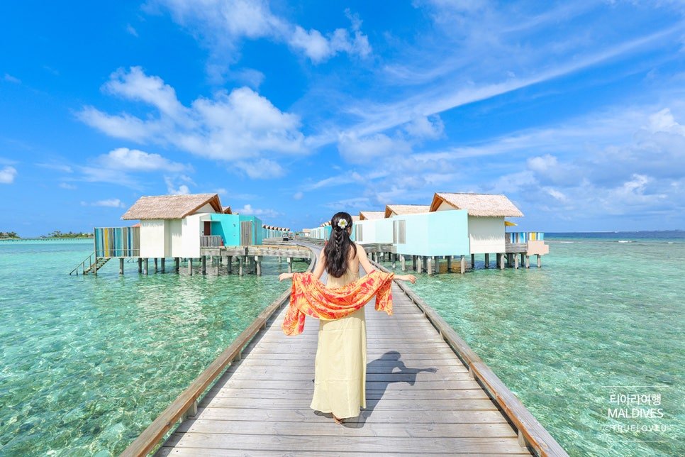 Woman in traditional dress walking on overwater bungalow boardwalk at Hard Rock Hotel Maldives