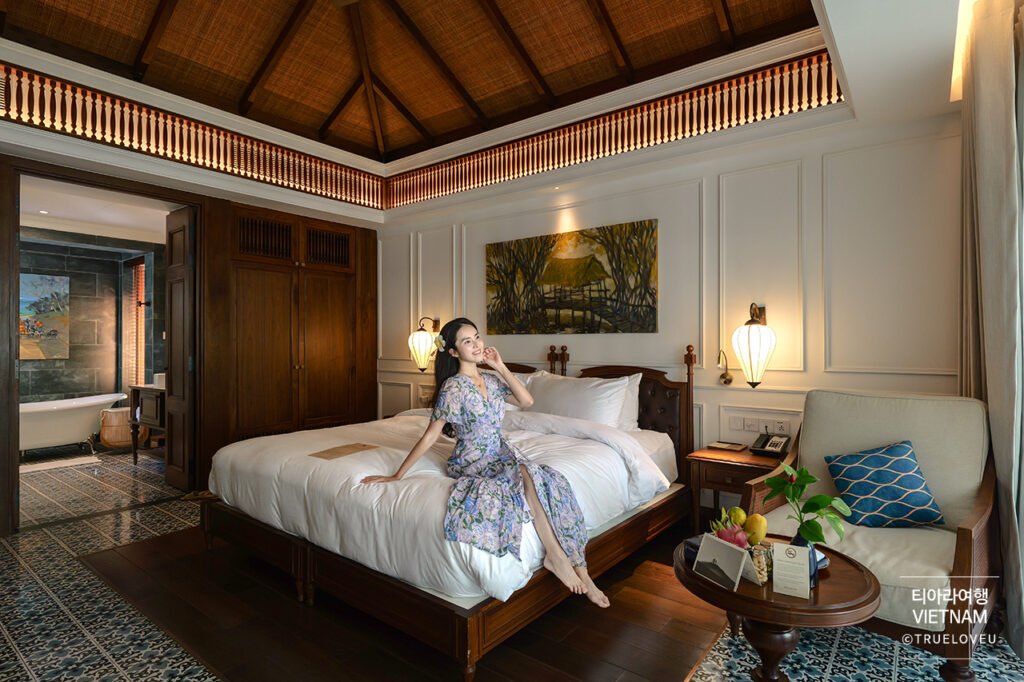 Woman relaxing on a bed in a luxury suite at The Anam resort in Mui Ne, Vietnam
