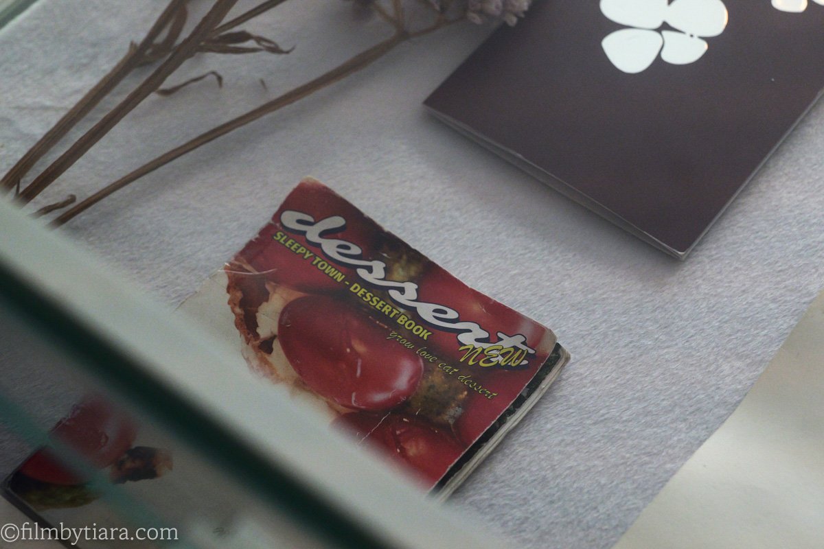 A worn dessert menu booklet labeled "Sleepy Town Dessert Book" displayed with dried flowers