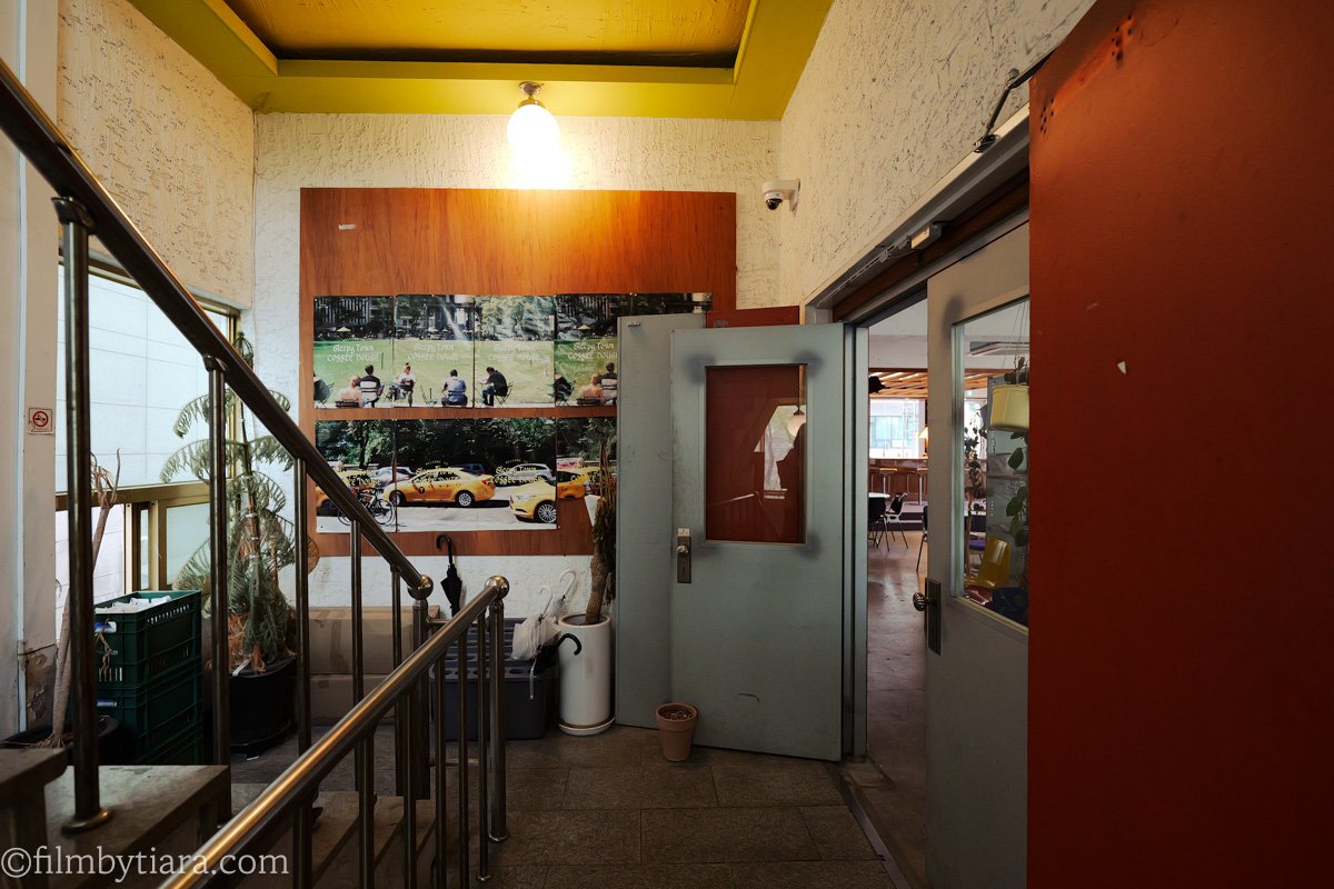 Staircase leading up to Sleepy Town cafe with framed street photography on the wall