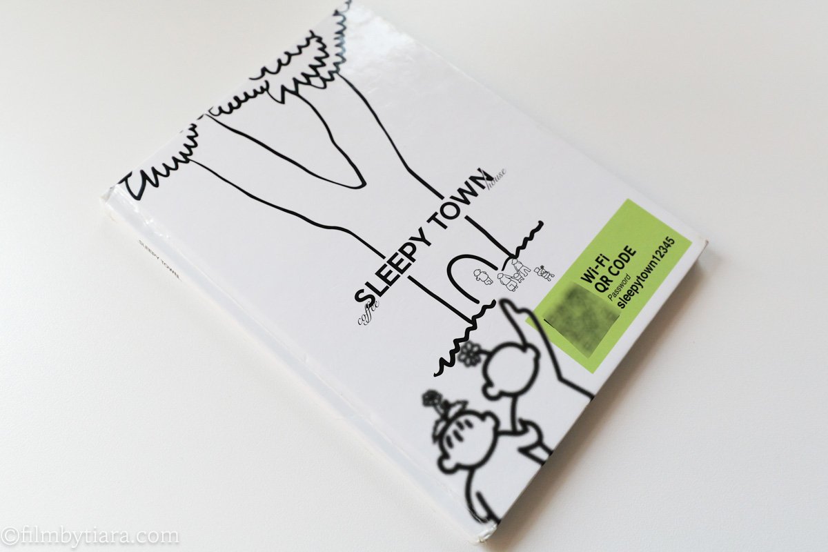Illustrated storybook-style menu cover for Sleepy Town coffee house with a Wi-Fi QR code sticker