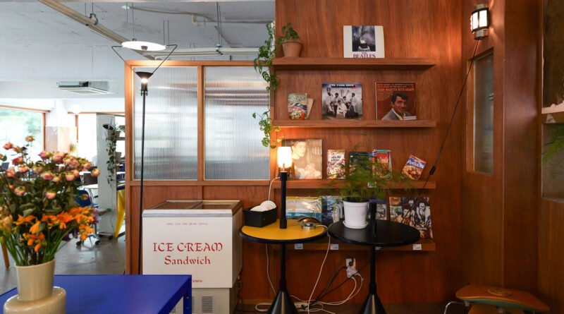 Retro wood-paneled shelf display with vinyl records and fresh flowers at Sleepy Town cafe, Daejeon