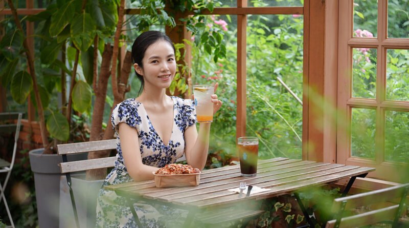 Woman seated at a wooden table inside The Fore's greenhouse dining room