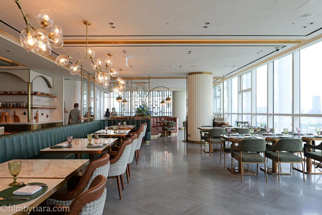 Restaurant Voisin dining room with green booth seating and river-view windows